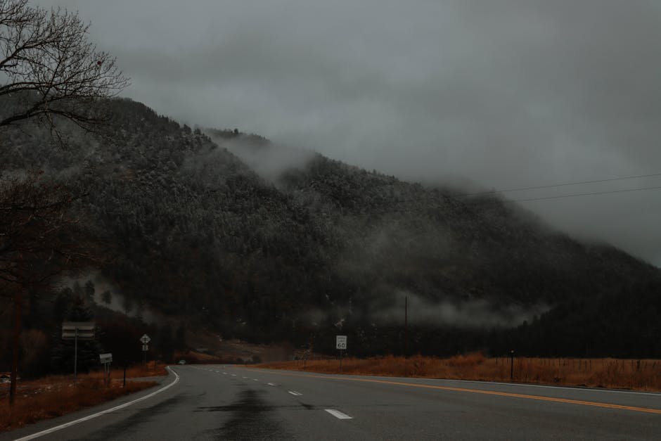 Dramatic mountain highway scene with mist and autumn tones in Colorado.