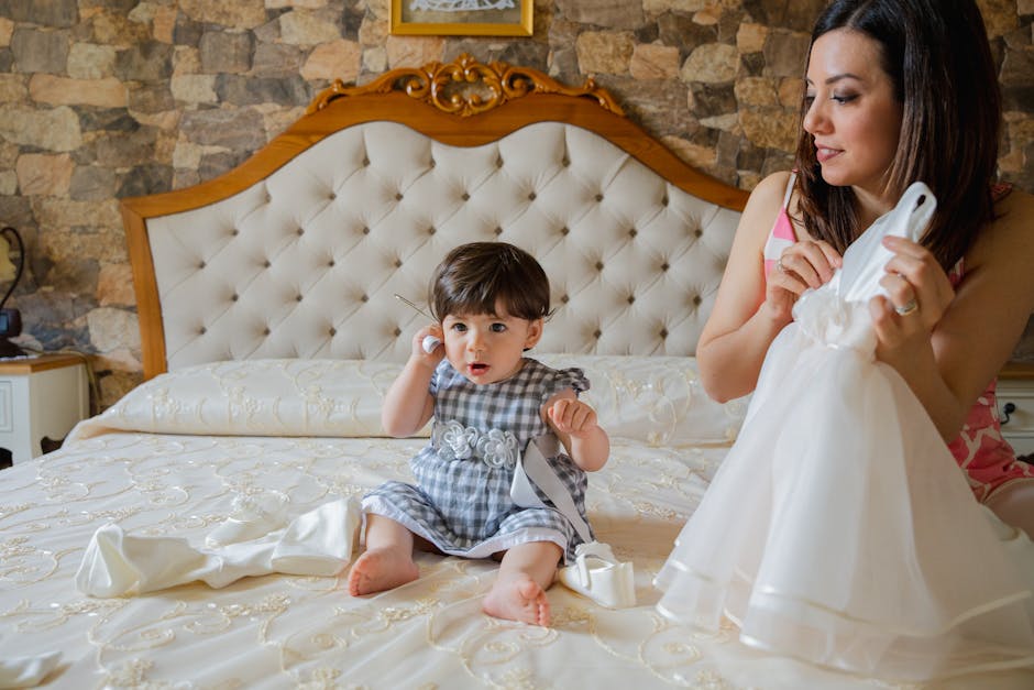 A mother and her baby sitting on a bed preparing for a special occasion together.