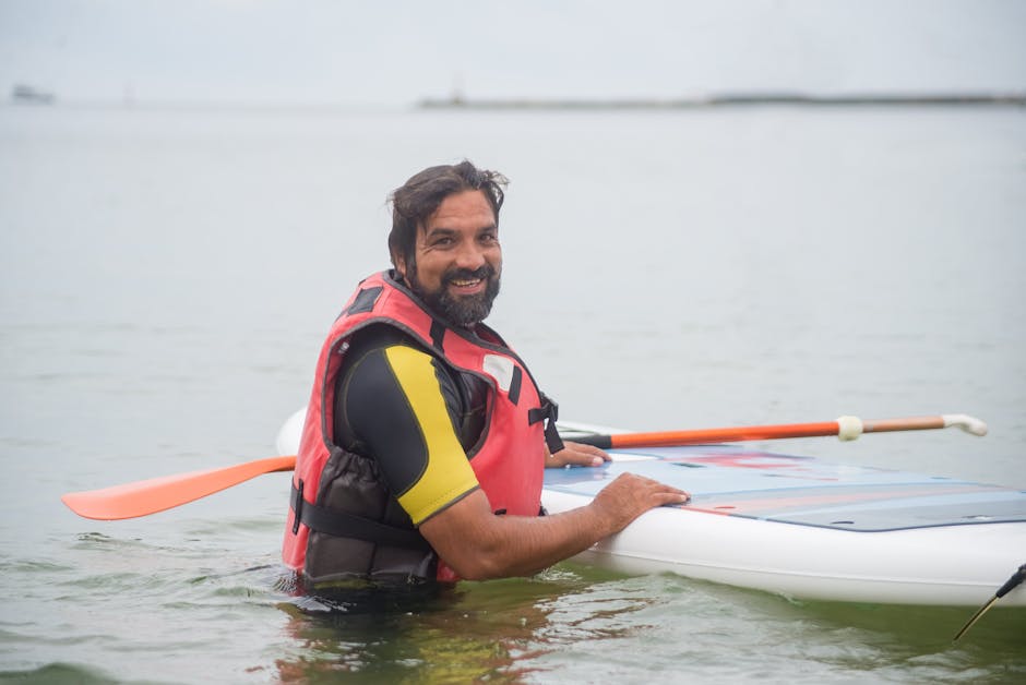 Smiling man in Portugal enjoying stand-up paddleboarding on a calm day.