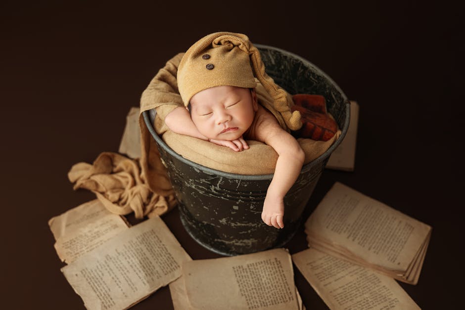 Sweet newborn sleeps in a vintage bucket surrounded by old books, creating a warm, peaceful scene.