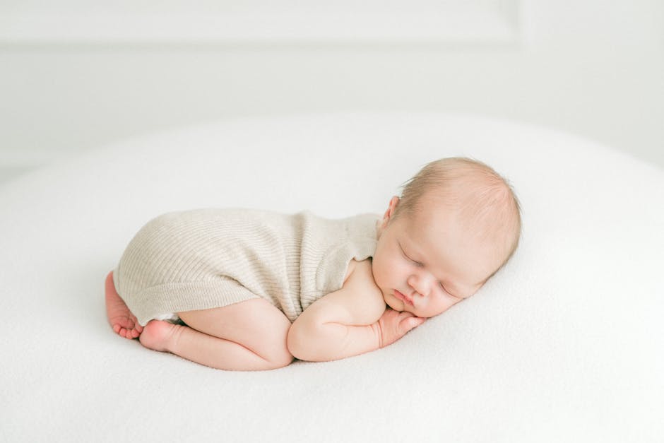 A serene photograph of a newborn baby peacefully sleeping on a white surface in soft lighting. (Photo: Goda Morgan) A serene photograph of a newborn baby peacefully sleeping on a white surface in soft lighting.
