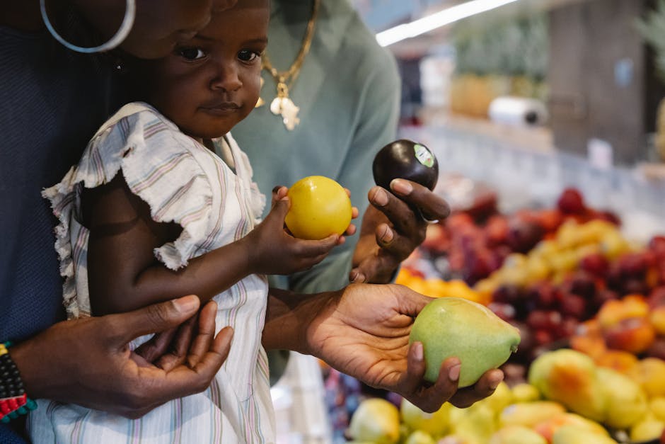 A young child and parent selecting fresh fruits together at a grocery store.