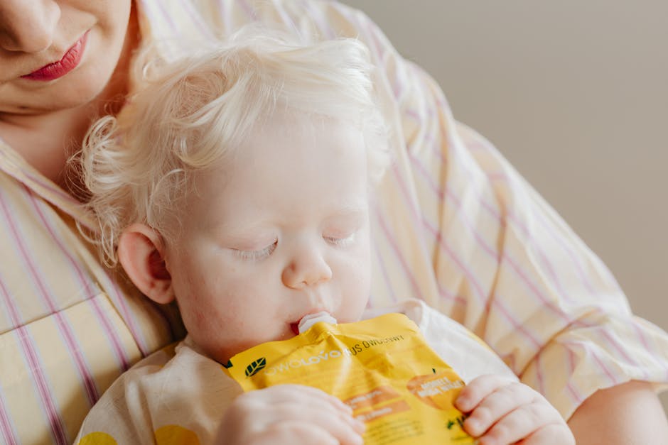 Close-up portrait of an albino toddler drinking a nutritional shake while being held.