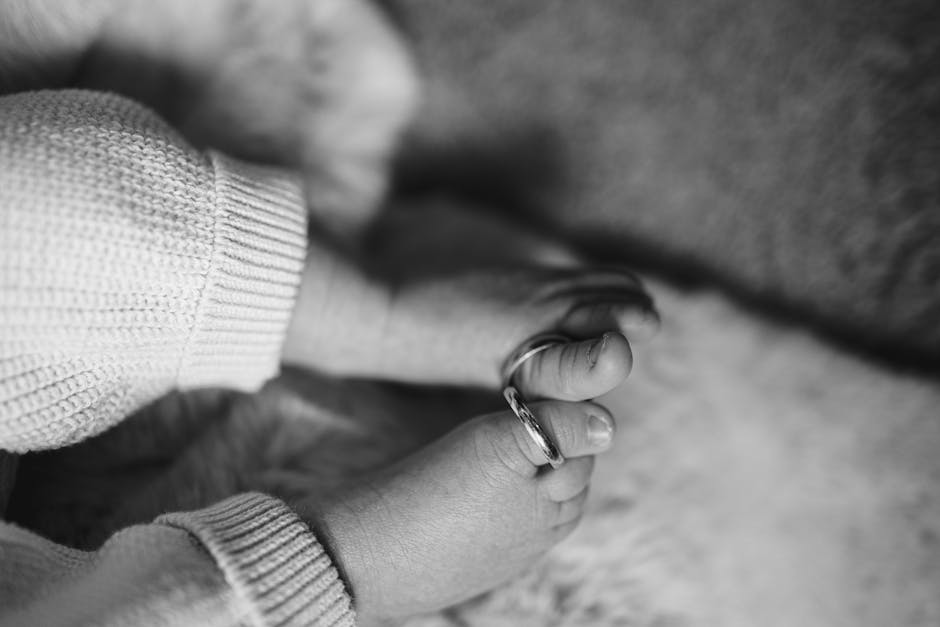A heartwarming close-up of baby feet wearing rings in black and white.