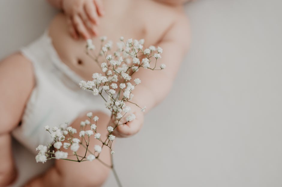 Portrait of a baby in a diaper delicately holding white flowers, emphasizing innocence. (Photo: Emma Bauso) Portrait of a baby in a diaper delicately holding white flowers, emphasizing innocence.