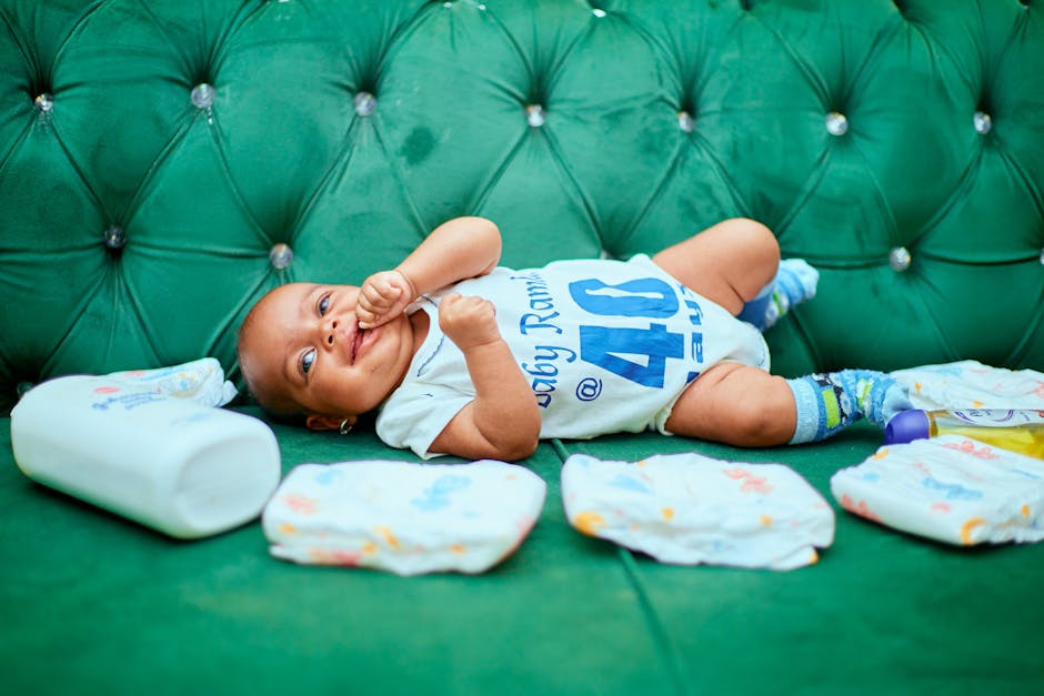 Adorable baby lying on a green sofa with diapers, showcasing a cute smile and playful demeanor.