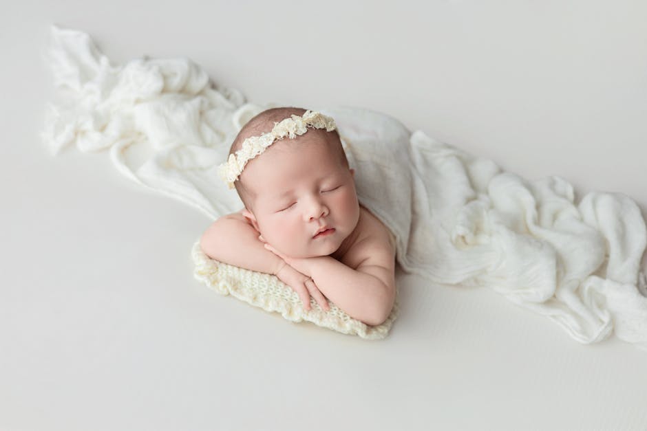 A serene newborn baby sleeping on a soft blanket in a cozy indoor art studio.