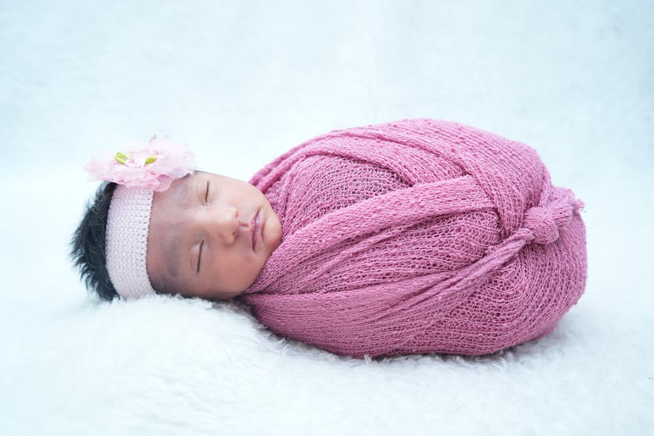 A peaceful newborn baby girl wrapped in a pink knitted blanket with a floral headband. (Photo: Prabhash Kumar) A peaceful newborn baby girl wrapped in a pink knitted blanket with a floral headband.