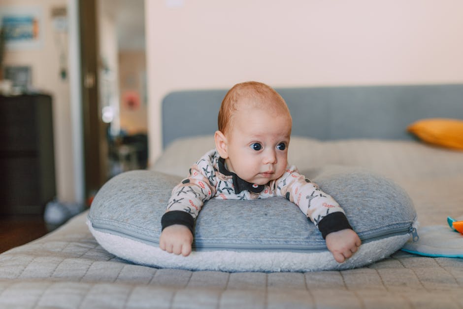 Charming baby lying face down on a soft pillow in a cozy indoor setting.