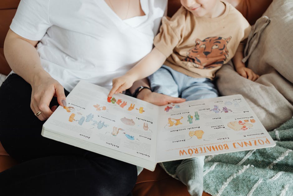 A mother and her son enjoy reading a children's book together while sitting on a cozy couch.