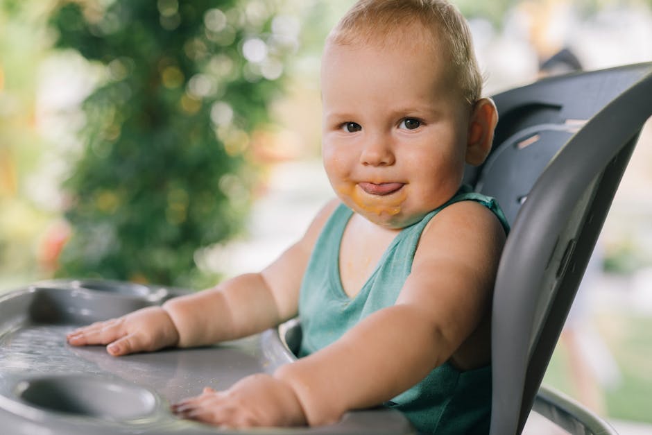 Charming toddler eating in a high chair outside, enjoying a sunny day.