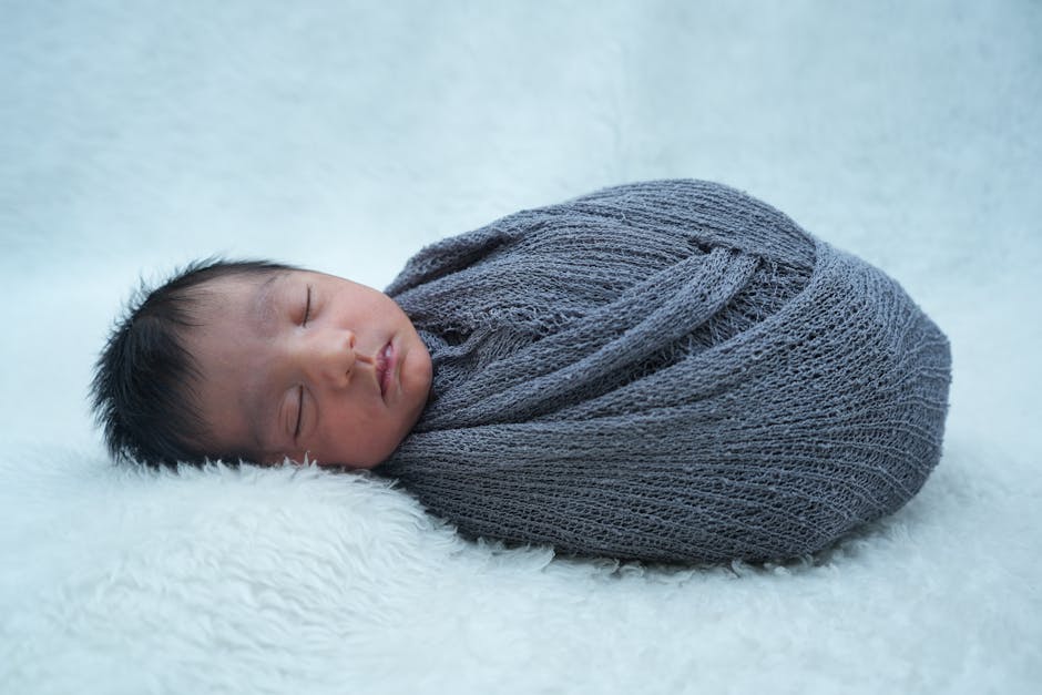 A serene newborn baby peacefully sleeping wrapped in a soft gray blanket. (Photo: Prabhash Kumar) A serene newborn baby peacefully sleeping wrapped in a soft gray blanket.