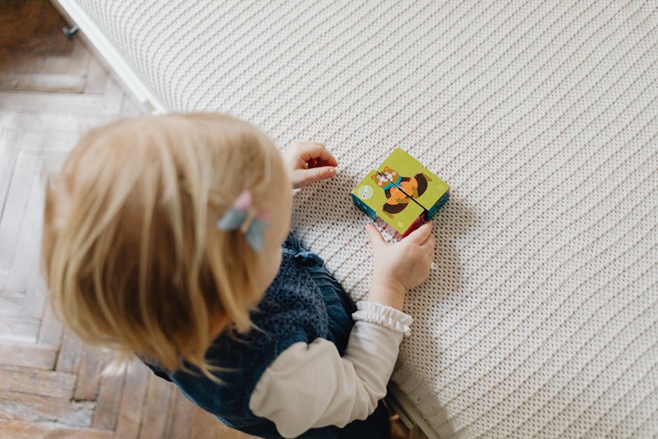 Young child engaged with colorful puzzle blocks on bed, learning through play. (Photo: www.kaboompics.com) Young child engaged with colorful puzzle blocks on bed, learning through play.