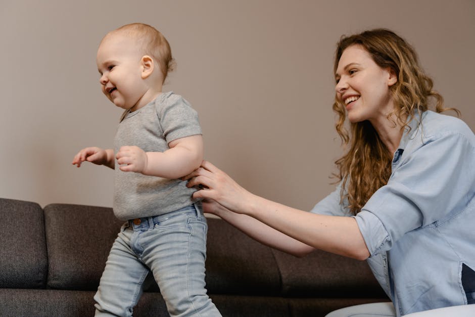 Smiling mother helping her toddler walk on a couch, capturing a special bonding moment.