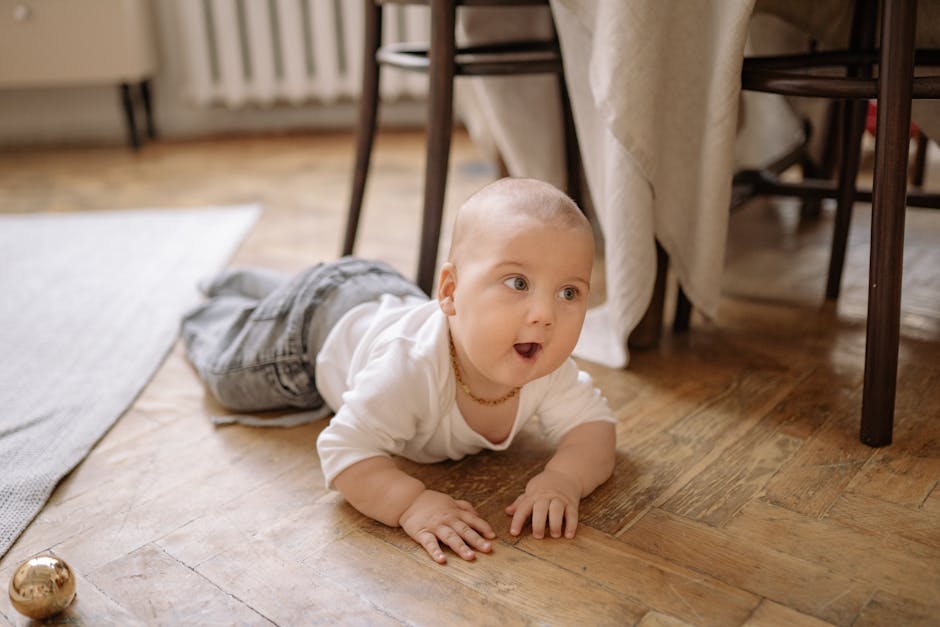 Cute baby in white crawling on wooden floor, showcasing curiosity and innocence.