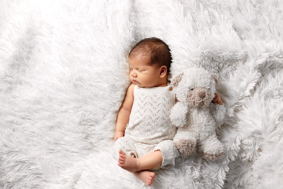 A peaceful newborn baby sleeps on a soft white blanket holding a plush teddy bear. (Photo: br prch) A peaceful newborn baby sleeps on a soft white blanket holding a plush teddy bear.