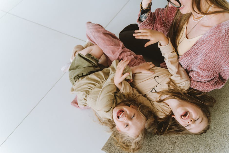 Mother and daughters laughing and bonding on the floor, capturing joyful family moments.